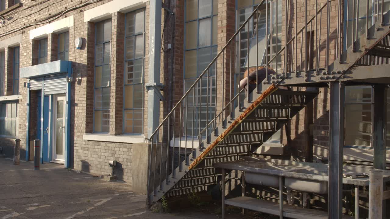 영국 남부 런던 햄의 코플랜드 로드에 있는 버시 빌딩 밖의 금속 계단에 앉아 있는 사람