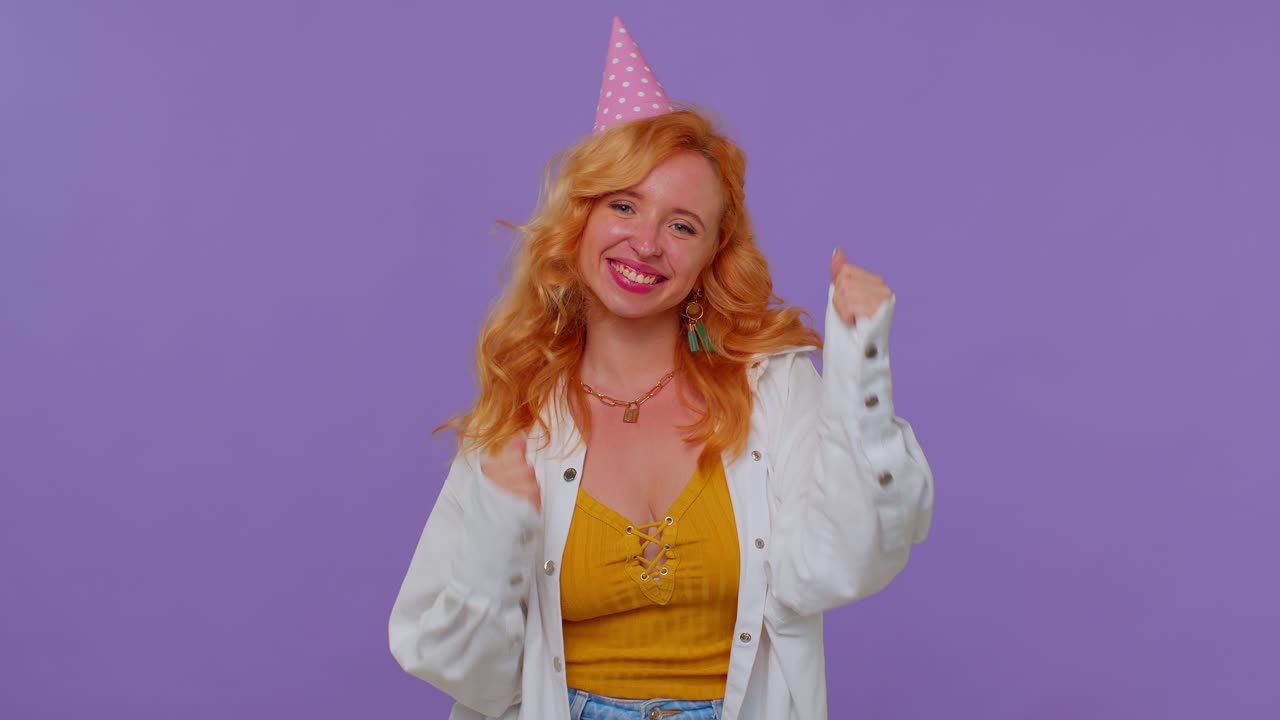 рыжая девушка в праздничной шляпе кричала, поднимая кулаки в жесте. я сделал это, празднуя успех, победу.