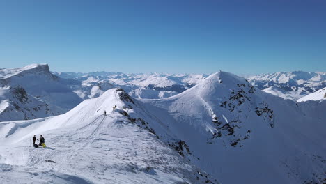 several cross country skiers taking a break along a ridgeline high up in the austrian alps, slow motion