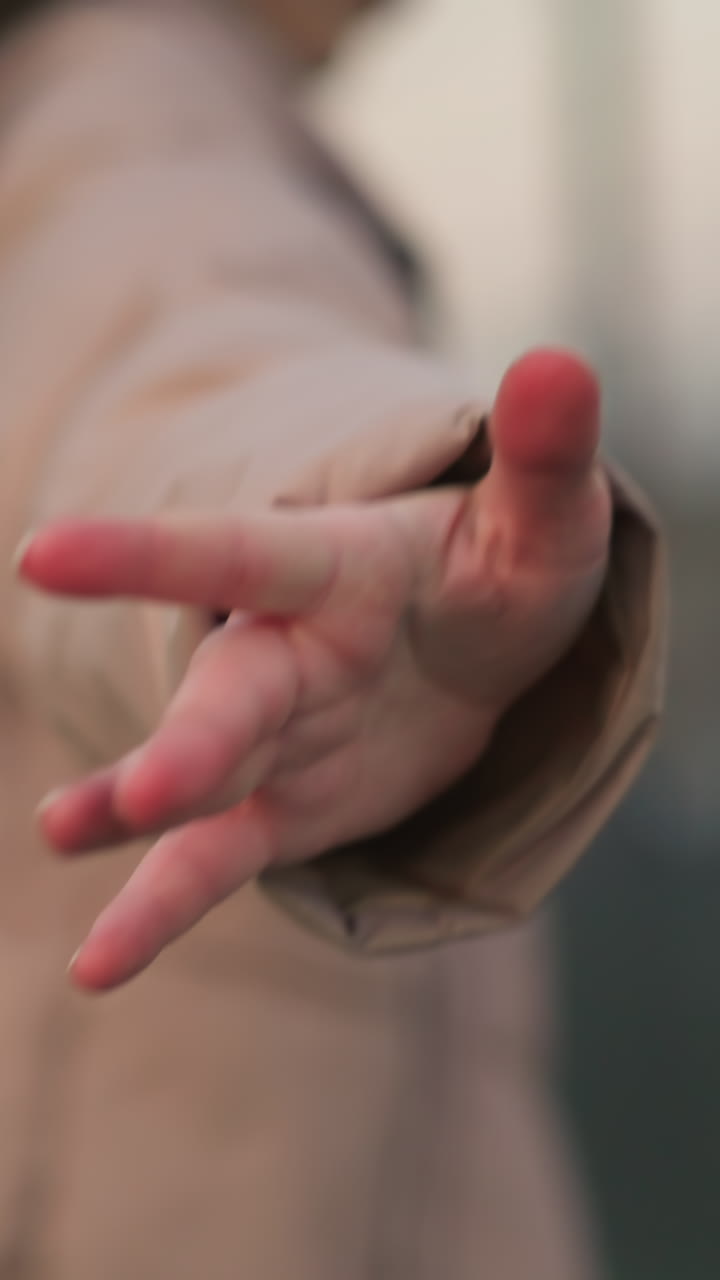 en una escena llena de enfoque suave, una persona con una chaqueta de melocotón extiende su mano alegremente hacia la cámara, creando un momento de interacción dinámica con el entorno.