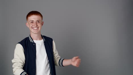 redhead boy looking at camera and pointing on copy space.