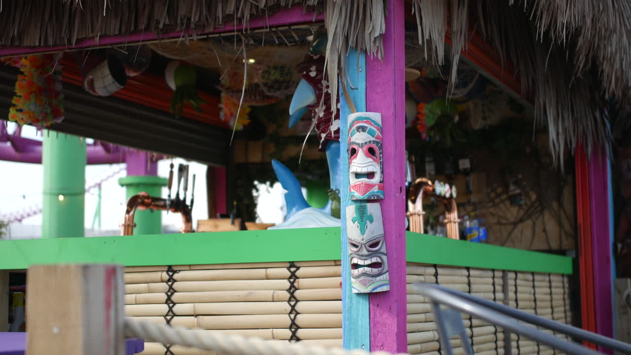 cerca de una barra de tiki de la playa con decoraciones coloridas, y diseños tradicionales de máscaras de madera