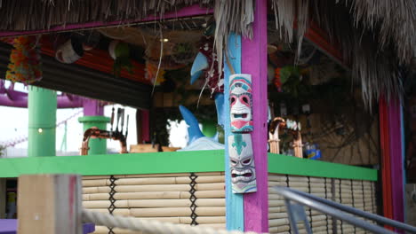 Close-up-of-a-beach-tiki-bar-with-colorful-decorations,-and-traditional-wooden-mask-designs