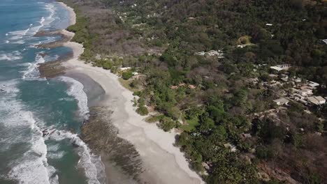 slow aerial footage flying away from the surf beach coast of santa teresa, costa rica