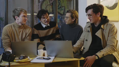 Businessmen-having-discussion-in-cafe.-Colleagues-looking-on-laptop-screen