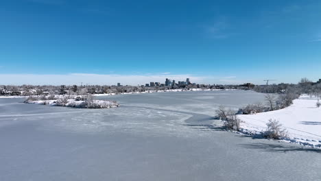 flying over a frozen sloan lake to reveal denver city during winter storm aerial drone shot