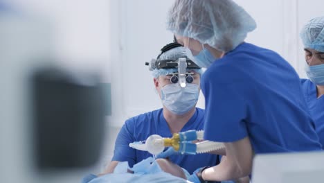 el anestesiólogo con asistentes prepara a la paciente femenina para la cirugía, pone a la paciente en anestesia, regula la máscara de oxígeno, el tubo endotraqueal. cirugía. anestesia