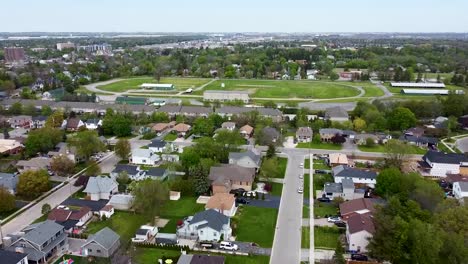 drone flying over milton houses towards a running track in summer