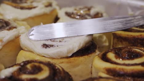 frosting freshly baked cinnamon rolls with cream cheese icing