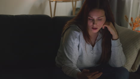 Anxious-Woman-Sitting-On-Sofa-At-Home-At-Night-Looking-At-Mobile-Phone-Concerned-About-Social-Media-Or-Bad-News-7