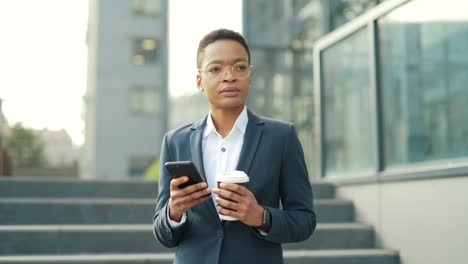 thinking confident business african american woman uses mobile phone smartphone standing near modern office center