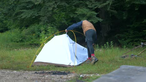 hombre desmontando tienda de campaña en un camping 4k