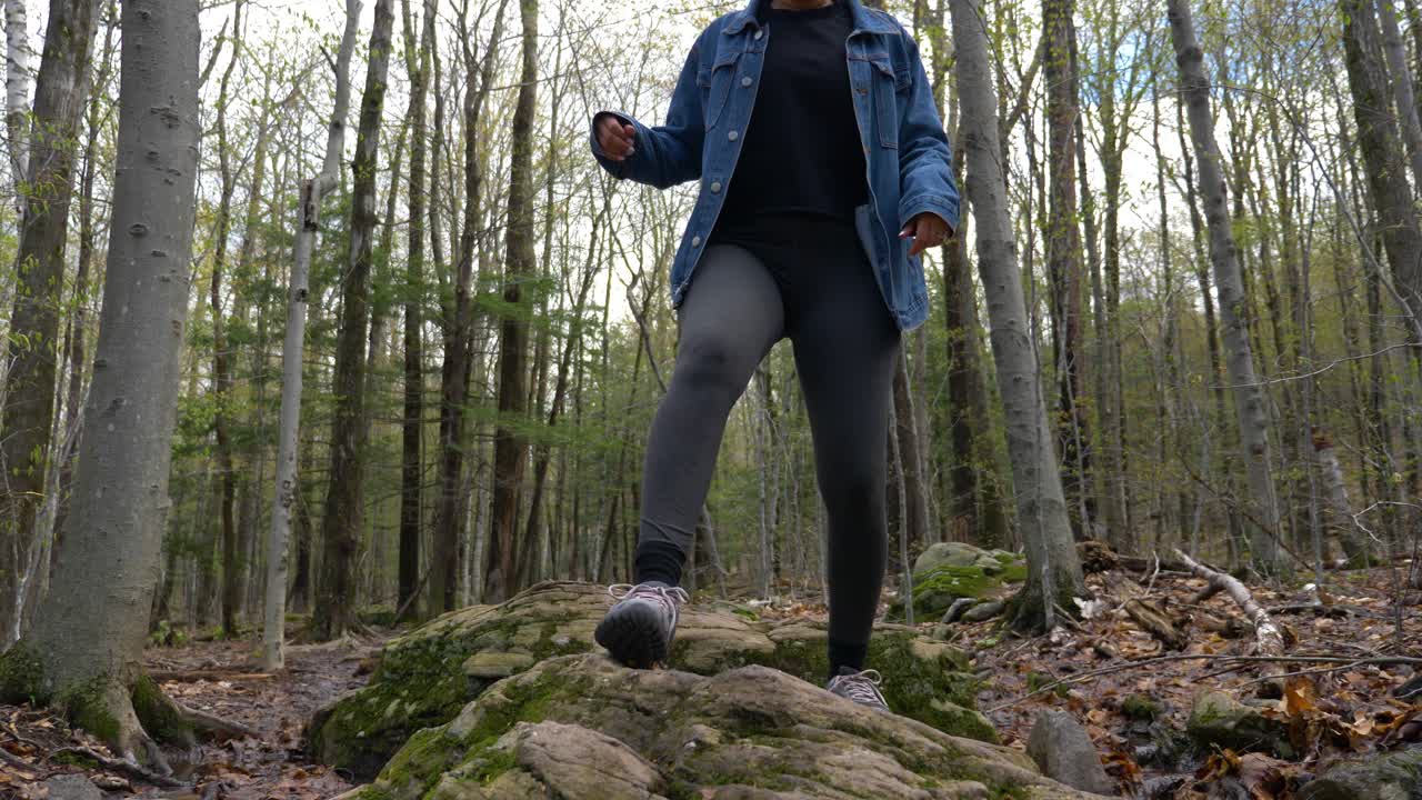 Ylöspäin katsottuna nuori, kaunis nainen seisoo ylpeänä ja luottavaisena New Yorkin osavaltion pohjoisosien metsäretkeilyreitillä.