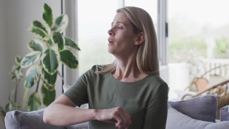 woman sneezing on her elbow at home