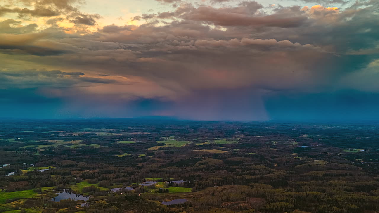 Aerial time-lapse of torrential rain moving over rural fields, stormy evening