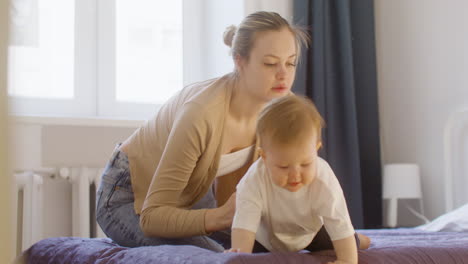 happy mother cuddling and playing with her baby boy on the bed at home 1