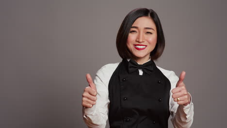 Smiling-waitress-giving-thumbs-up-sign-in-front-of-camera