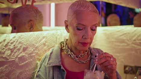 senior model drinking alcohol cocktail closeup. thoughtful stylish woman in cafe