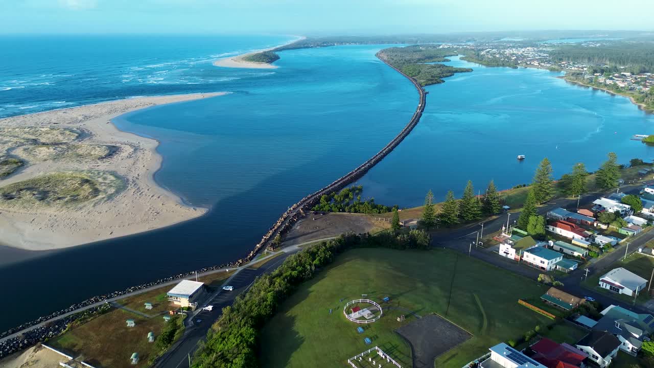 Drone aerial landscape of Harrington break wall waterfront with sandy ocean beach dunes and rural town housing along the main street near Taree NSW Australia travel tourism holidays infrastructure