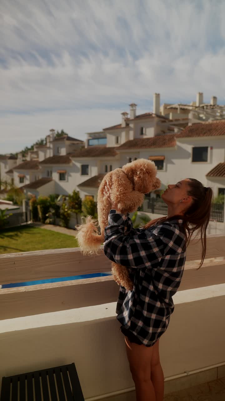 mujer acurrucando a su perro en un balcón