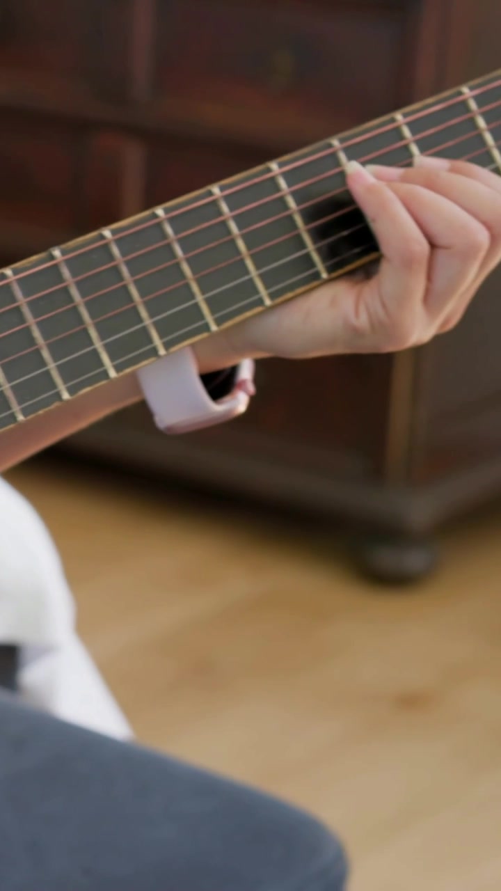 Wideo pionowe: Nagrywanie, gdy kamera ustawia ostrość, lewa ręka ćwiczy akordy na gitarze w sypialni.