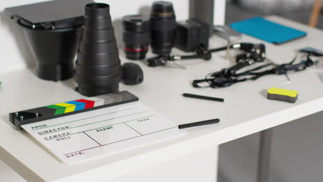 close up de película clapperboard o pizarra con lentes de cámara y accesorios de iluminación rodando película o video en estudio