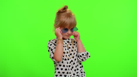 Portrait-of-funny-playful-blonde-child-girl-in-white-black-shirt-wearing-sunglasses,-charming-smile