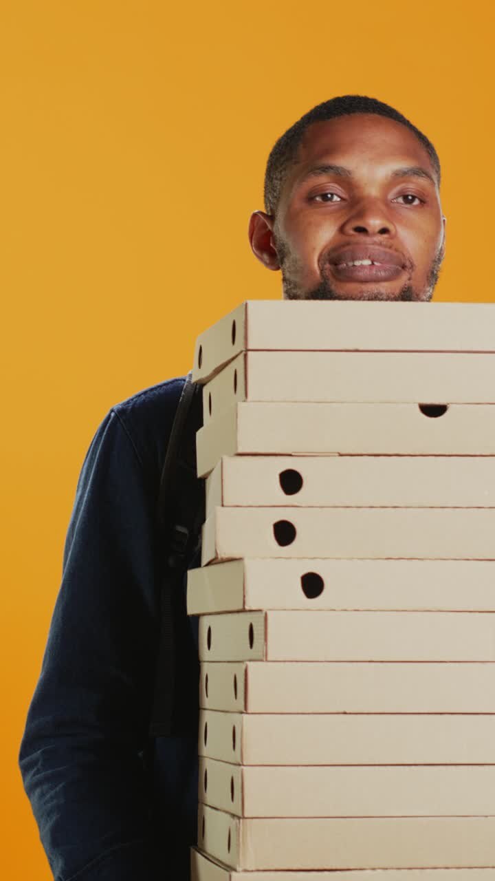 Fattorino alle prese con una pila alta di cartoni della pizza