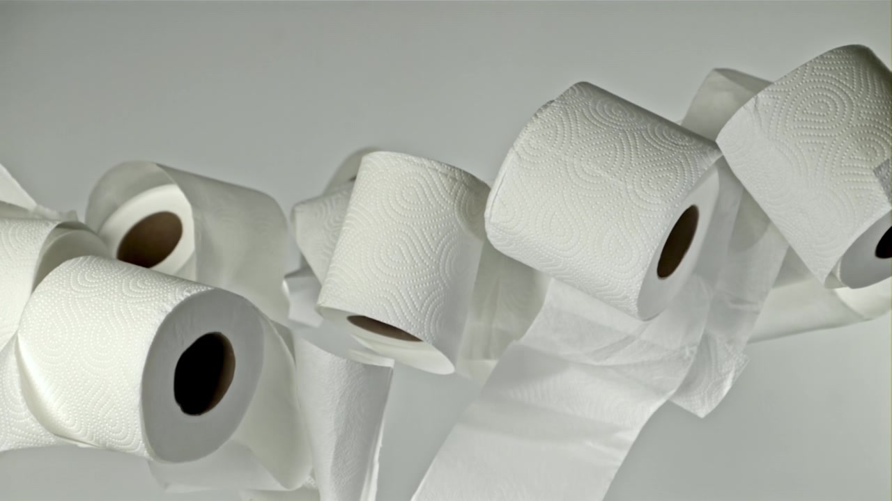 White Toilet Paper Rolls Falling and Piling Up on a Grey Background