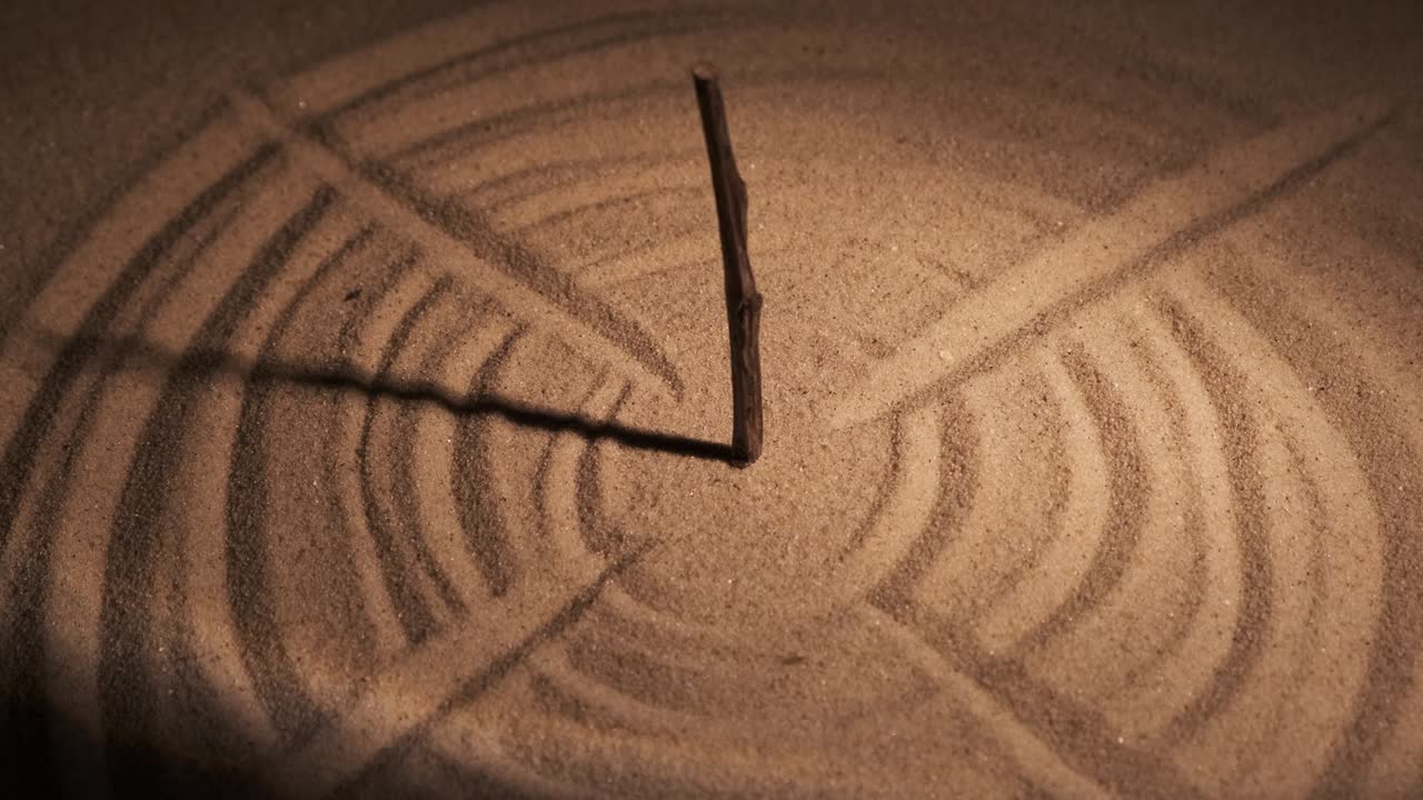 태양 시계처럼 스타일링 된 막대기, 태양 광선 및 모래의 원