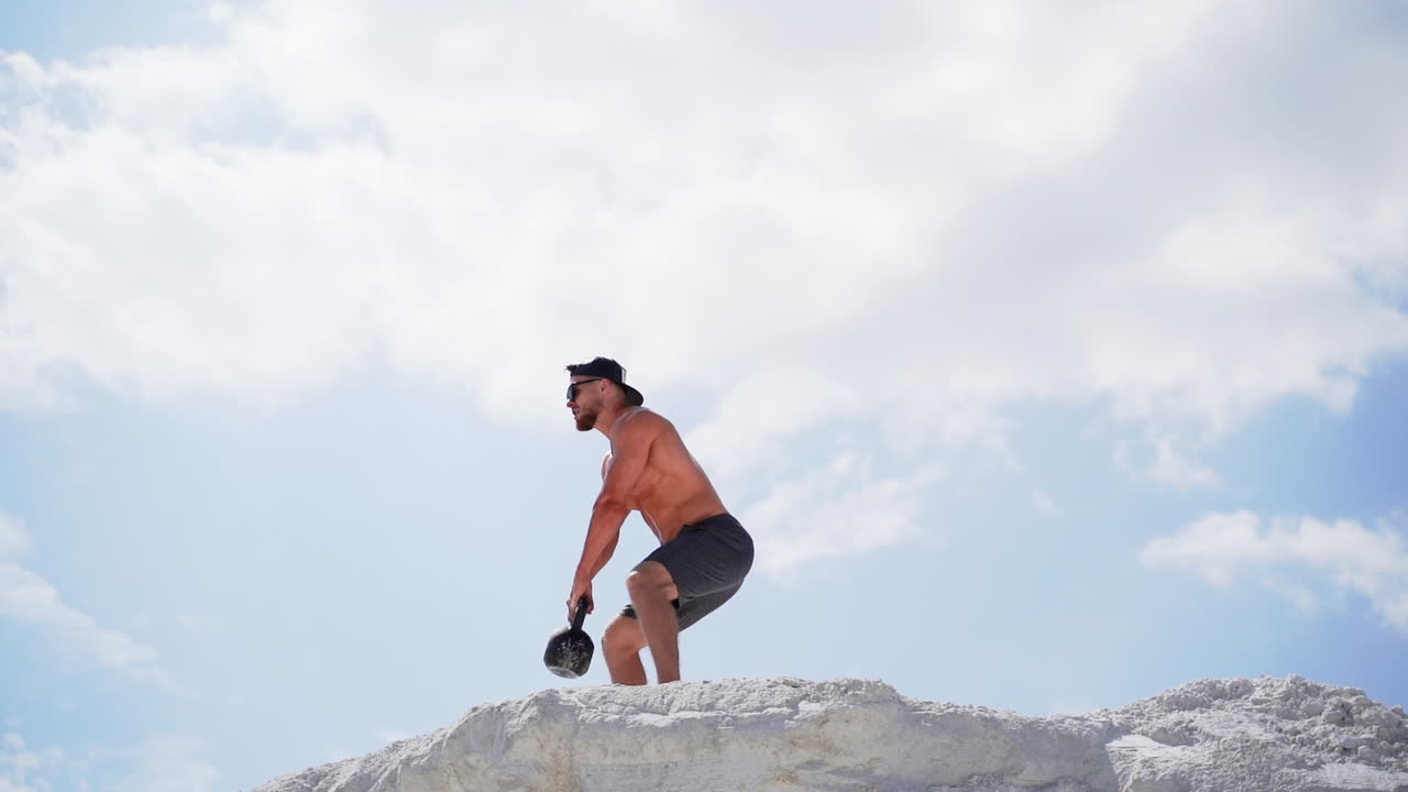Homem fazendo treino com kettlebell. Atleta treinando e fazendo exercícios ao ar livre.