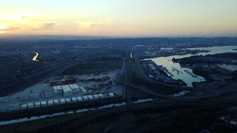 footage-of-sunset-overlooking-yachts-moored-with-traffic-on-a-road-and-shipping-containers-to-be-transported-to-ships-by-trucks