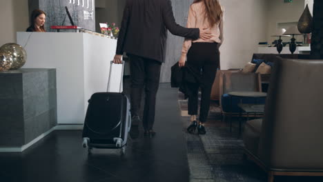Business-couple-with-suitcase-arriving-on-hotel.-Man-check-in-hotel-reception