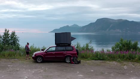 Viajero-Con-Carpa-En-La-Azotea-Estacionada-A-Lo-Largo-De-La-Orilla-Del-Lago-En-El-Campamento-De-Sifjord,-Noruega