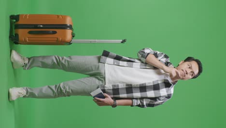 full body of asian male traveler with luggage and passport thinking and looking around then raising her index finger while standing in the green screen background studio