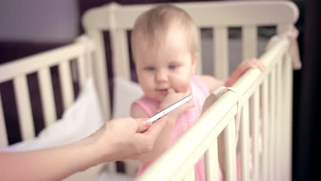 niña en la cama de bebé. bebé lindo buscando teléfono inteligente. niño pequeño en la cama