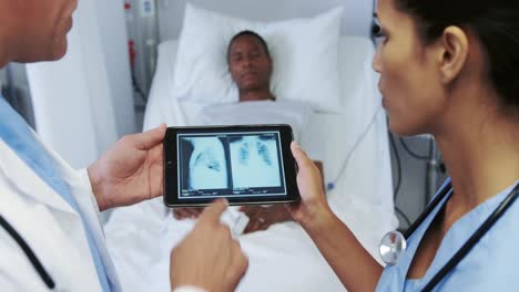 primer plano de médicos multiétnicos discutiendo el informe de rayos x en una tableta digital en una sala del hospital