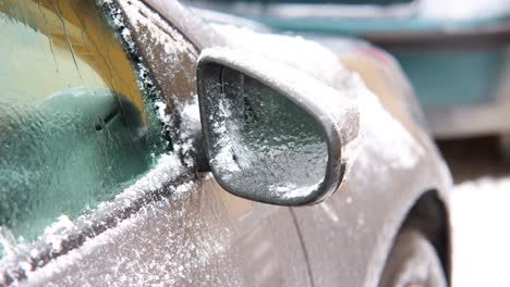 close up of right side mirror of a parked car with snow defrosting