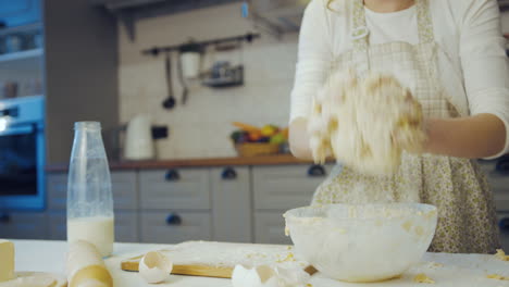 Close-up-of-the-young-Caucasian-woman-kneading-a-daugh-in-a-glass-bowl-in-the-cozy-modern-kitchen.-Portrait-shot.-Indoor