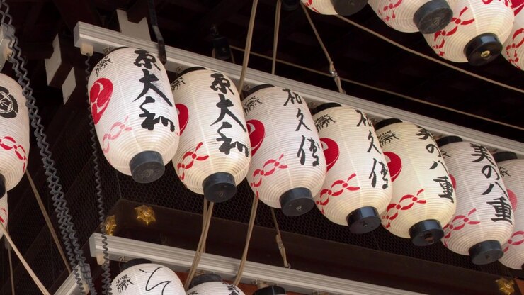 File di lanterne di carta bianche e rosse pendono sotto le gronde di un tempio a Kyoto, Giappone