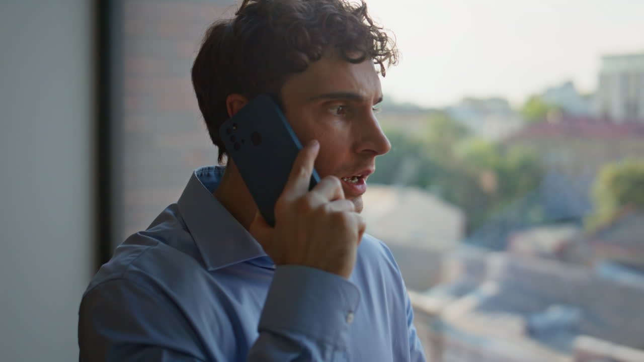 Portrait angry ceo calling cellphone at office window. Nervous businessman