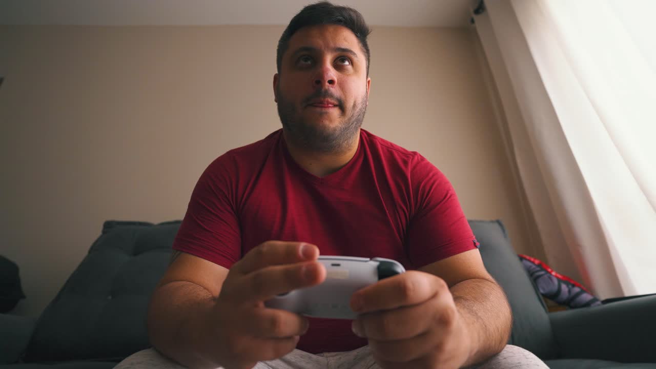 adulto joven centrado en jugar videojuegos con controlador de consola en sus manos