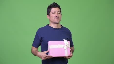 happy hispanic man thinking while holding gift box