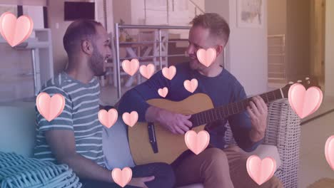 Animation-of-hearts-over-diverse-male-couple-playing-guitar