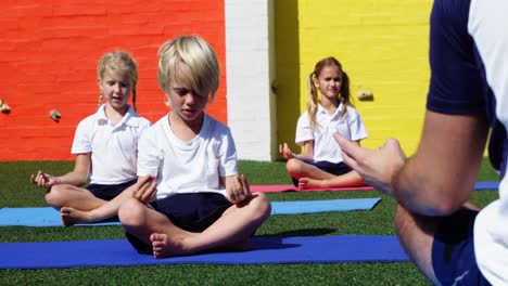 yoga instructor instructing children in performing yoga