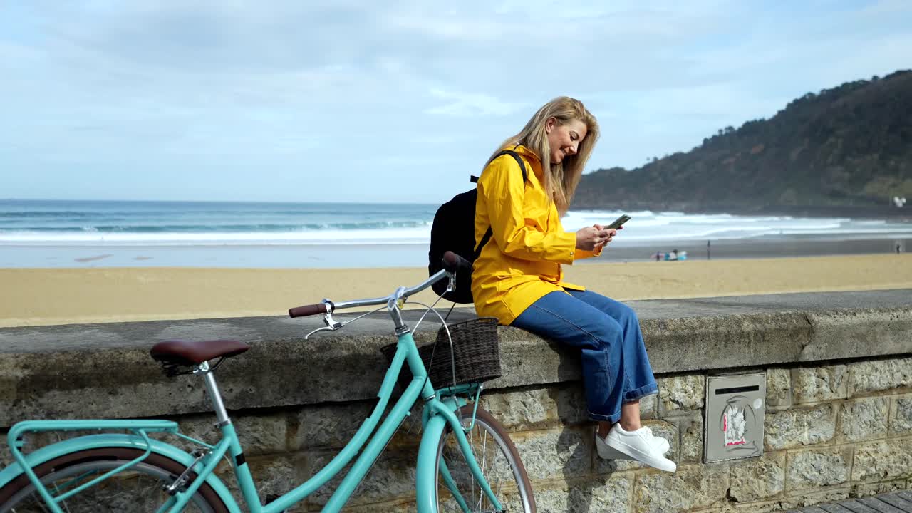 Woman with Bicycle Using Mobile Phone by the Beach