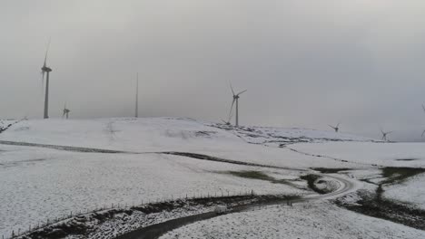 Winter-mountain-countryside-wind-turbines-on-rural-highlands-aerial-view-cold-snowy-valley-hillside-slow-orbit-right