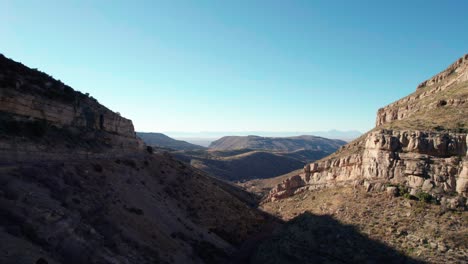 Drone-aerial-view-panning-to-the-right-of-a-large-valley-with-cliffs