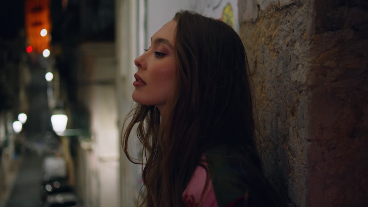 chica turista inclinada muro edificio de la ciudad tarde en la noche primer plano. dama en la ciudad de la noche