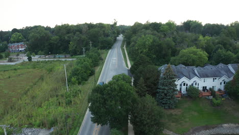 elevated aerial footage following a car as it travels down a suburban neighborhood of america